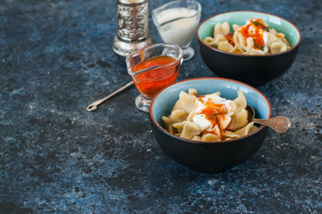Turkish raviolli in bowls with tomato and yogurt sauces.