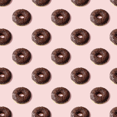 Colorful seamless pattern of chocolate donuts with light pink background. Sweetness pastel colors. Confectionery banner.