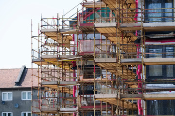 Scaffold and red net surrounding house renovation for safe access to refurbishment height