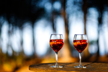 2 calici  di vino con dei cocktail colorati che riflettono lo sfondo di natura e alberi
