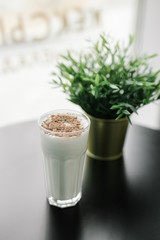 milkshake with chocolate chips on a background of black table and greenery