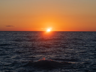 Epic sunset (dawn) on the sea. Waves are breaking on stones.