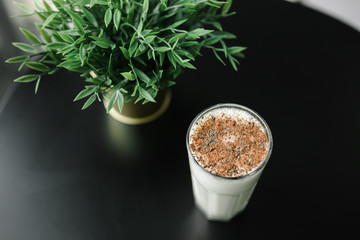 milkshake with chocolate chips top view on a background of black table and greenery