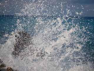 White foam and splash of sea waves. Waves breaking on a pier in windy weather.