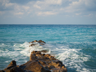 Fototapeta na wymiar Waves roll over a stone pier. Seascape on a cloudy day.