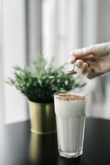 the milkshake is sprinkled with chocolate chips on a background of black table and greenery