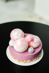 purple cake with pink and blue chocolate balls on a black table