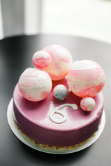purple cake with chocolate balls of different sizes and the number six