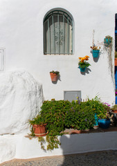 The charming Spanish village of Frigiliana.  Pretty flowers in traditional pottery at a small village house on a sunny summers day.  The town is typical of the ‘white’ villages of southern Spain.