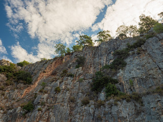 View of the impregnable high rock from below, from the sea. Seashore.