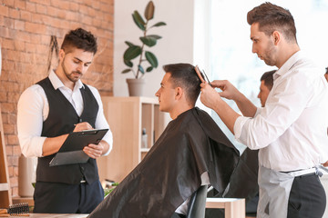 Young man with professional hairdresser and model during courses in salon