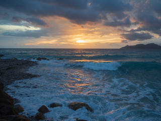 Epic sunset (dawn) on the sea. Waves are breaking on stones.