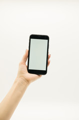 Woman's hand  holds a black phone with white screen on white background.