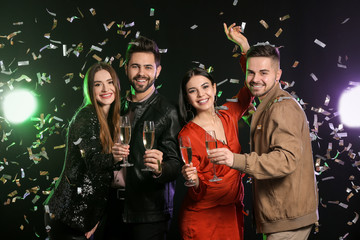 Happy people with glasses of champagne on dark background