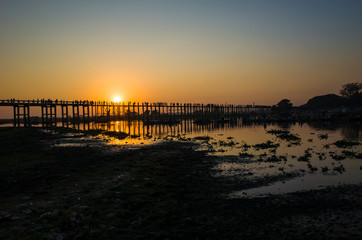 Fototapeta na wymiar Silhouette of U Bein bridge with reflection in water at sunset in Amarapura, Mandalay, Myanmar