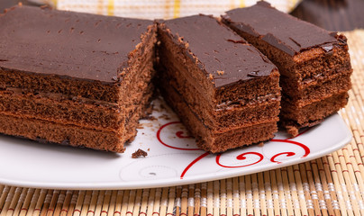 Sliced chocolate cake on a plate on the table. Close up.