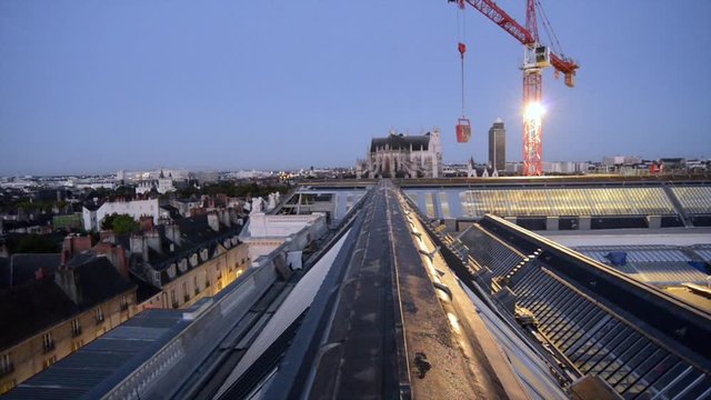 Une grue de chantier reprend le travail au lever du jour sur les toits de la vielle ville de Nantes 