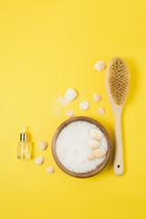 sea salt and a stiff body brush on a yellow background. home skin care for cellulite. concept skin care in spring, home Spa, care products.