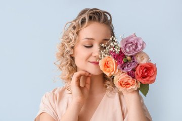 Beautiful young woman with bouquet of flowers on color background