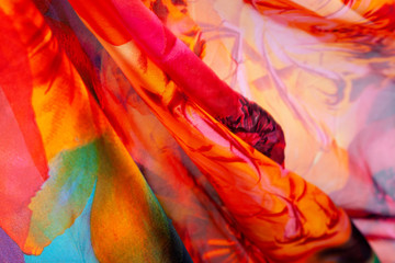 Fabric natural silkworm silk, Chinese silk, bright colors-red, orange, yellow, green. Floral ornament. It flows in the sun. Texture, background, Wallpaper, close-up.