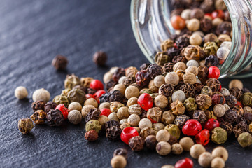 mix of peppercorns on a dark stone background