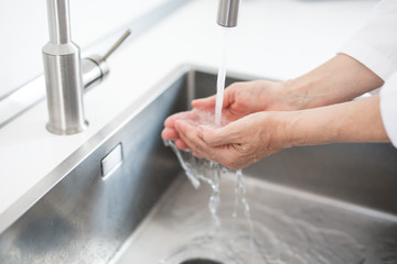 Frau wäscht Hände unter fließendem Wasser

