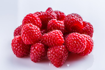 Juicy fresh natural raspberries on white acrylic background