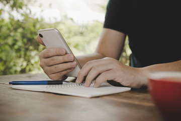 young man relaxed working with digital mobile smart phone and report document with red coffee cup on desk at cafe restaurant, work from home, digital technology, internet, business financial concept