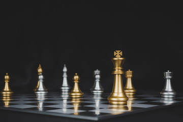 Winner. shot of gold king surrounded with silver chess pieces on chess board game competition with dark background, chess battle, victory, success, team leader, teamwork and business strategy concept