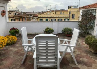 Terrace with table and chairs, flowers and views of the city. Roma, Italy