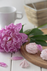 Pink marshmallow and pink peony on a white wooden table