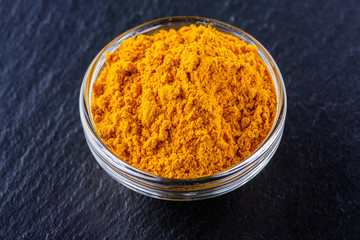 natural turmeric powder on a dark stone background