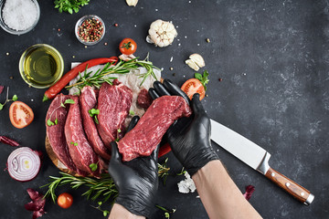 The butcher shows a piece of portioned steaks from the total portion of steaks that lie on...