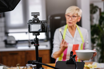 Elderly woman baking for her online streaming cooking channel. Older woman vlogging
