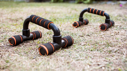 Two pushup handles for exercise on dry grass at a yard.