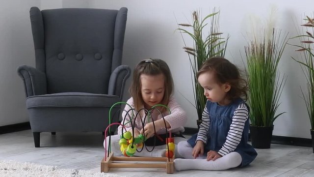 Two beautiful sisters play with a multicolored toy (Montessori technique)