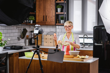 Elderly woman baking for her online streaming cooking channel. Older woman vlogging