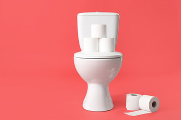 Toilet bowl with rolls of paper on color background