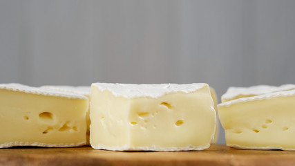 pieces of soft cheese Camembert on light grey background. Delicious pieces of white mold cheeses with soft textures Camembert close up, macro
