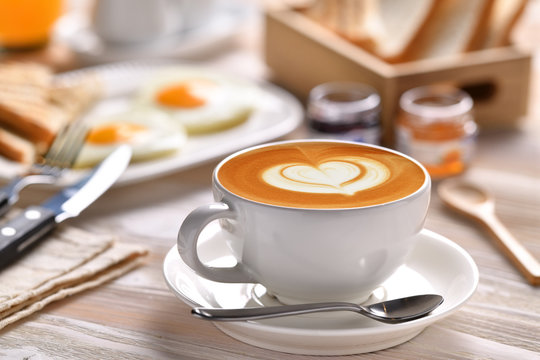 Cup of coffee latte with breakfast on wooden table