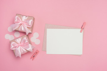 Gift boxes with pink ribbon bow and blank postcard on pastel pink background. Banner mock up for Women's day, Birthday or Mothers Day. Best gift for women concept. Top view, flat lay with free space. 