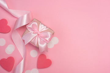 Gift box with pink ribbon bow on pastel pink background with white confetti and hearts. Banner for Valentines day, Birthday or Mothers Day. Best gift for women concept. Top view, flat lay free space. 