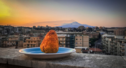 Arancino on a plate with landscape and the city behind it