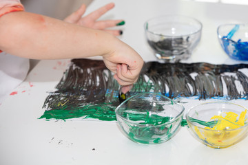 Close up young boy painting with colorful hands. Art, creativity and painting concept