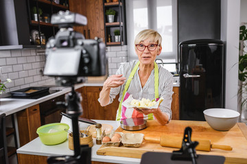 Fototapeta na wymiar Elderly woman baking for her online streaming cooking channel. Older woman vlogging