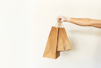 Close-up paper packages or bags holding by delivery man hand in front of white background. Food...