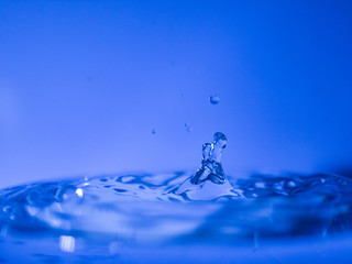 Water drop creating waves ripples and air borne water droplet