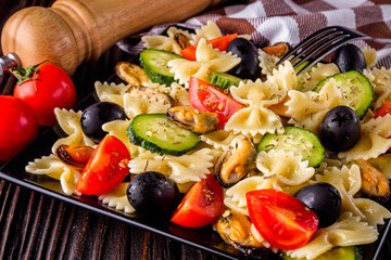 Delicious pasta salad with tomato cucumber and olives on wooden rustic background