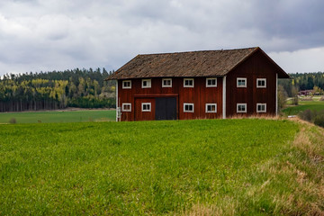 Fototapeta na wymiar Nykoping, Sweden A red barn on a field in the spring.
