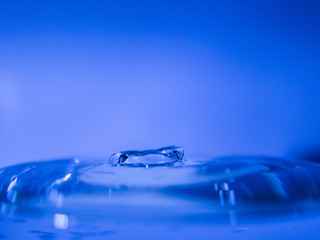 Water drop creating waves ripples and air borne water droplet